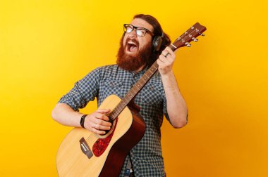 Sakallı müzisyen hipster adam akustik gitar çalmak.