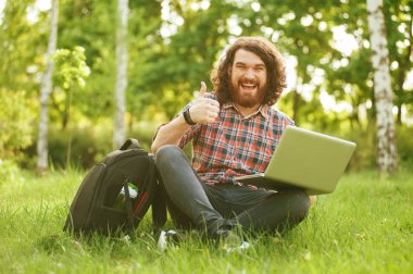 Mutlu sakallı hippi adam, park gösteren başparmak dışında öğrenci