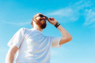 Gülümseyen gökyüzü arka plan üzerinde gözlüklü hipster adam sakallı