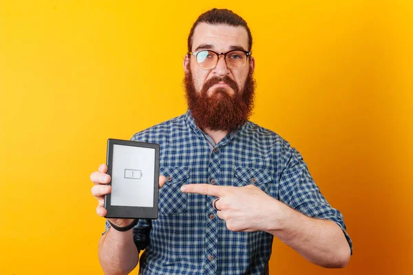Triste hombre barbudo, batería baja en la tableta. concepto de batería —  Fotos de Stock