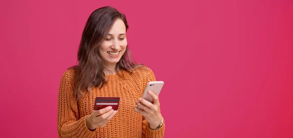 Joyeux jeune femme utilisant son smartphone et tenant sa carte de crédit, mobile web banking — Photo