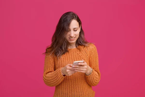 Foto de mujer feliz usando smartphone y usando suéter amarillo — Foto de Stock