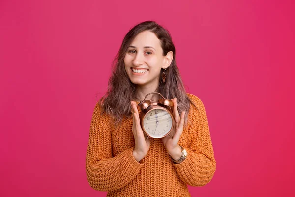 Happy smiling woman in sweater holding alarm clock — Stock Fotó