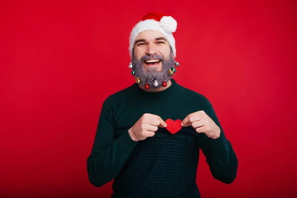 Lächelnder bärtiger Hipster-Mann in Weihnachtsstimmung mit rotem Herzen — Stockfoto