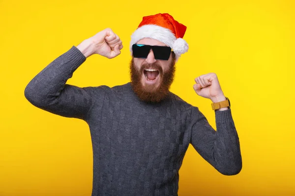 Photo of cheerful man with beard and santa claus hat celebrate victory over yellow background — Zdjęcie stockowe