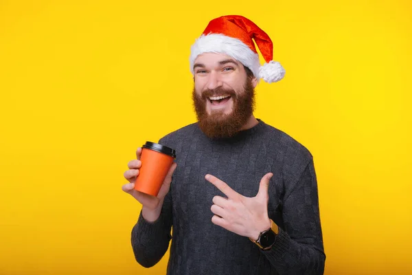 Uśmiechnięty szczęśliwy człowiek z brodą wskazujący na filiżankę kawy na wynos — Zdjęcie stockowe