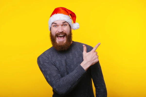 Radosny podekscytowany mężczyzna z brodą i kapeluszem Świętego Mikołaja wskazującym — Zdjęcie stockowe
