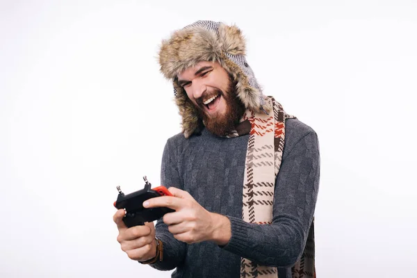 Alegre homem hipster barbudo feliz em roupas de inverno jogando jogos no smartphone e usando joystick — Fotografia de Stock