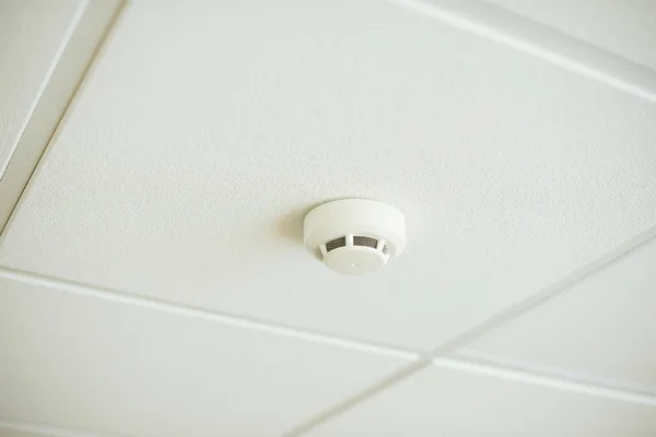Smoke and fire detector on white ceiling