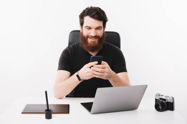 Sakallı adamın portresi akıllı telefonuyla oturuyor.