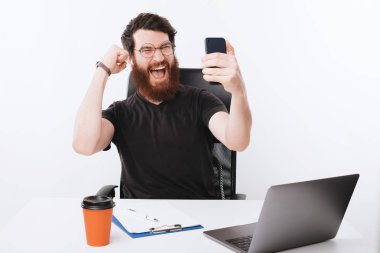 Harika bir ofis çalışanı iş yerinde oturup başarıyı kutluyor.