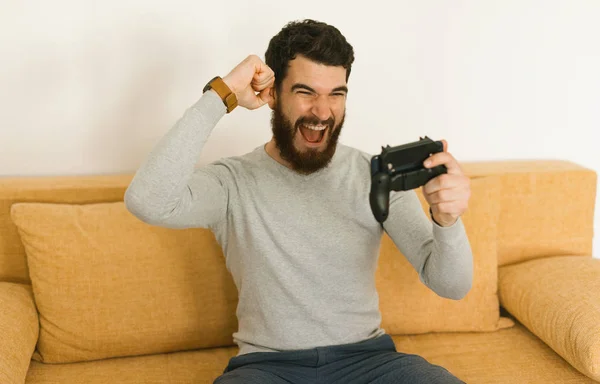 スマートフォンでゲームを支払いながら勝利を祝う素晴らしい男 — ストック写真