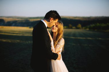 Gün batımında kucaklaşan bir çiftin güzel fotoğrafı.