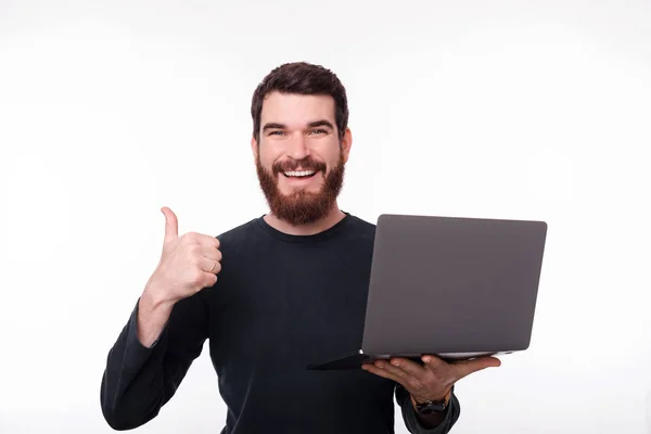 Foto von glücklichen bärtigen Kerl, der einen Laptop hält, während er auf die Kamera schaut — Stockfoto