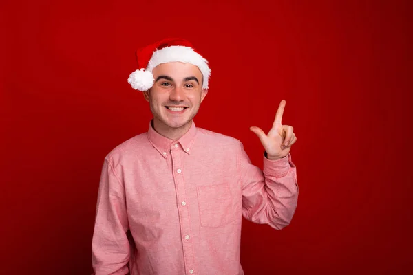 Veselý muž v Santa Claus klobouk stojící nad červeným pozadím a — Stock fotografie