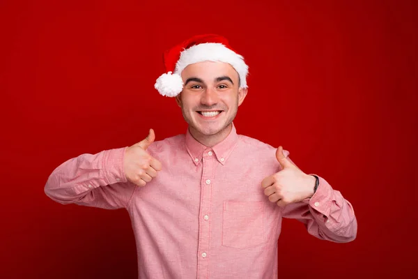 Щасливий молодий чоловік у червоній сорочці показує великі пальці вгору жестом і варі — стокове фото