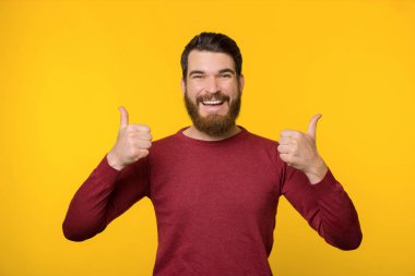 Sarı arka planda dikilen neşeli sakallı adam.