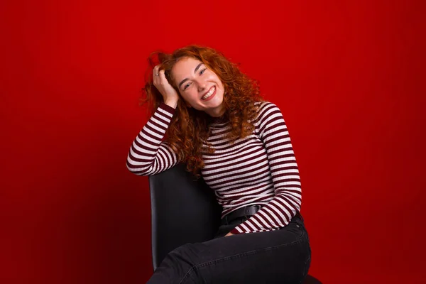 Photo of foxy young woman, sitting in chair and smiling at camer