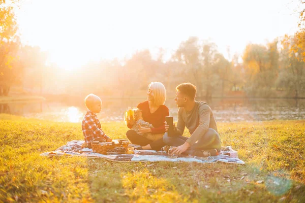 Μια ευτυχισμένη οικογένεια κάνει πικνίκ μαζί κοντά σε μια λίμνη στη μέση ενός πάρκου.. — Φωτογραφία Αρχείου