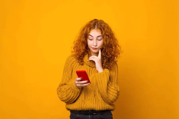 Jovem mulher em suéter amarelo olhando frustrado no smartphone — Fotografia de Stock