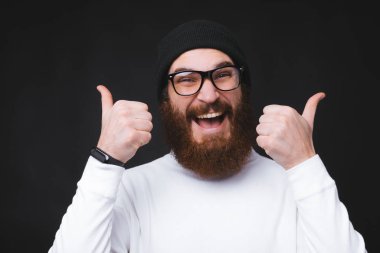 Gülümseyen genç bir adamın baş parmağı gösteren bir portresi.