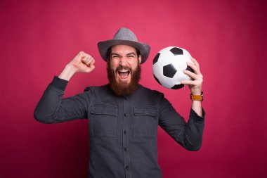 Futbol topu tutan ve başarıyı kutlayan adamın fotoğrafı.