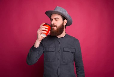 Gri şapkalı ve kahve içen sakallı adam.