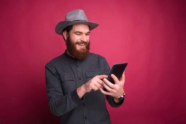 Cheerful young man surfing on internet and holding tablet — Stock Photo, Image