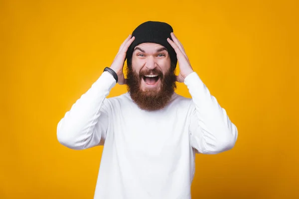 Fotó meglepett szakállas hipster férfi áll sárga háttér — Stock Fotó