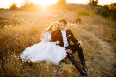 Mutlu genç çift gün batımında sahada vakit geçiriyorlar, birlikte oturuyorlar..