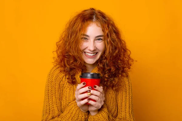 Retrato de chica pelirroja, emocionada sosteniendo una taza para llevar, y de pie sobre un fondo aislado — Foto de Stock