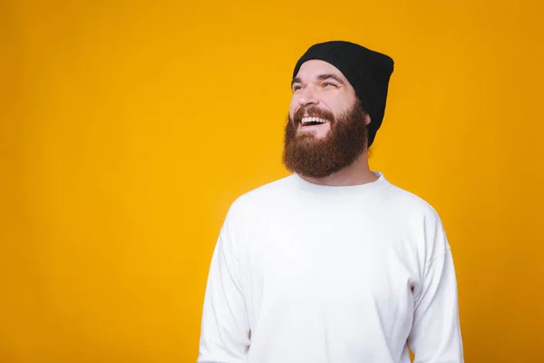 Barbudo jovem está olhando para longe e sorrindo no fundo .yellow . — Fotografia de Stock