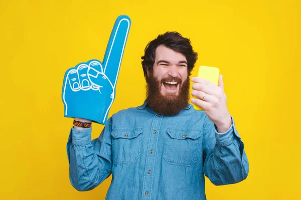 Joven alegre en camisa azul mirando el teléfono inteligente y celebrando —  Fotos de Stock