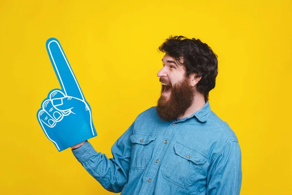 Photo of screaming man pointing away at copyspace with fan foam glove