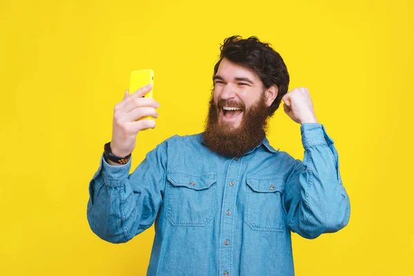 Heureux jeune homme à la mode regardant smartphone et célébrer — Photo