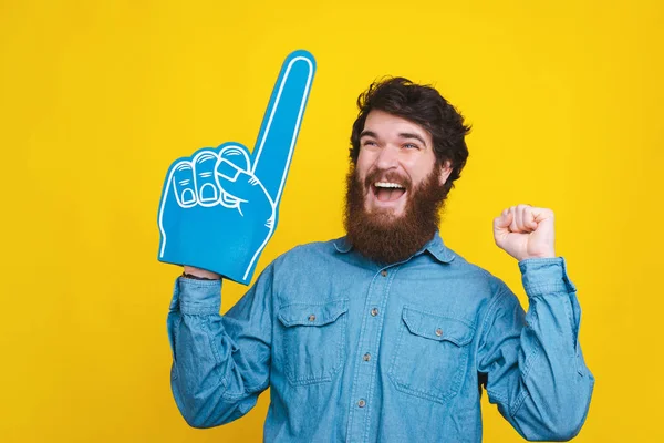 Hombre alegre en camisa azul celebrando con el guante de espuma del ventilador — Foto de Stock