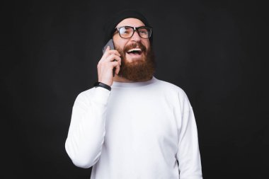 Telefonla konuşan neşeli ve gülümseyen bir adamın fotoğrafı.