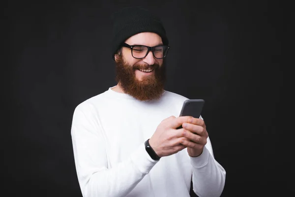 Joyeux bel homme avec barbe utilisant son téléphone — Photo