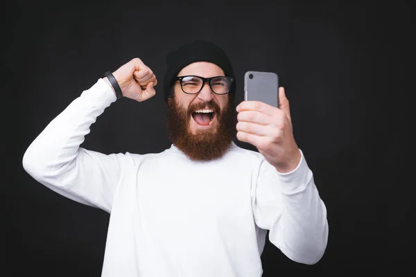 Homem bonito incrível celebrando e olhando para o smartphone — Fotografia de Stock