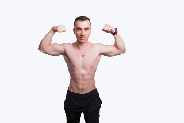 Handsome strong athletic man standing with his hands up near a white wall. — Stok fotoğraf