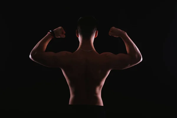 Foto do fisiculturista flexionando seu bíceps, visão traseira — Fotografia de Stock