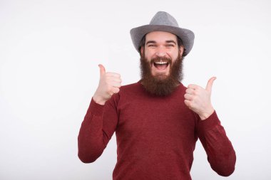 Portrait of amazed young bearded man showing thumbs up