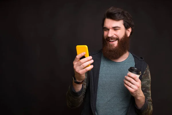 Photo of young man using smartphone and holding cup of coffee to go — Stock Photo, Image
