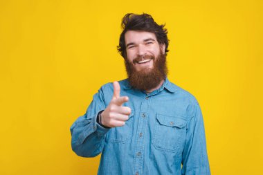 Cheerful young man with beard pointing at the camera