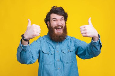 Amazed man in blue shirt showing thumbs up and scream