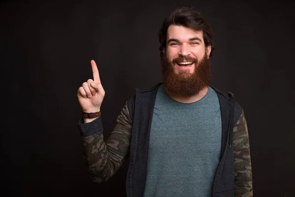 Feliz hombre sonriente apuntando hacia el copyspace sobre el fondo oscuro —  Fotos de Stock