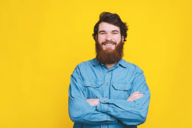 Sarı B 'nin üzerinde duran çapraz kollu gülümseyen adamın portresi.