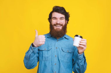 Neşeli adam baş parmak işareti yapıyor ve elinde beyaz bir fincan... 