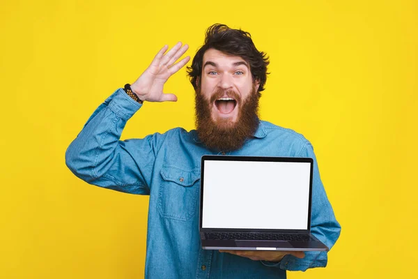 Foto de hombre barbudo asombrado mostrando la pantalla blanca en el ordenador portátil — Foto de Stock