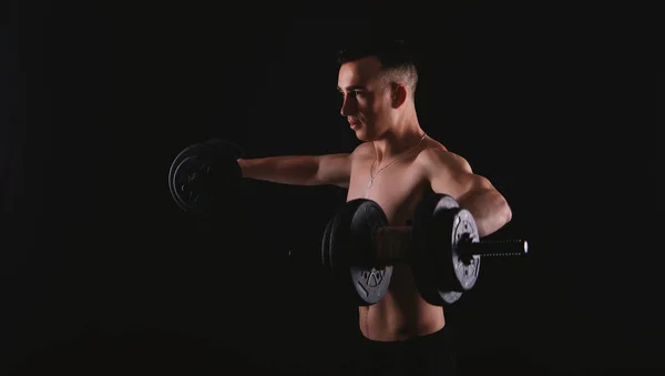 Photo of young man doing exercise with dumbbells over dark backg — 스톡 사진